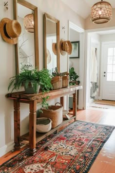 the entryway is decorated with plants and baskets on top of an antique table, along with mirrors