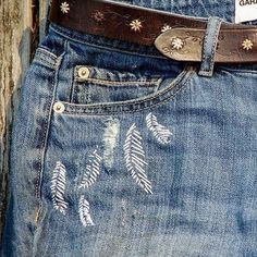 a pair of jeans with white feathers on them