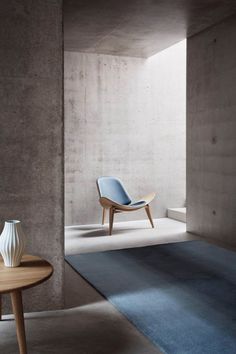 a chair sitting on top of a blue rug next to a table with a vase