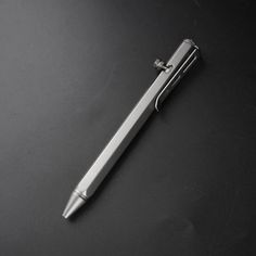 a silver pen sitting on top of a black table