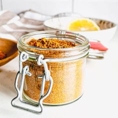 a glass jar filled with spices sitting on top of a counter next to spoons