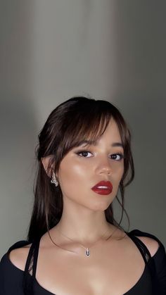 a woman with long hair wearing a black top and red lipstick on her lips is posing for the camera