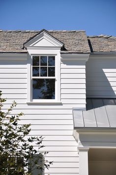 an image of a white house with a window on the roof and a tree in front of it