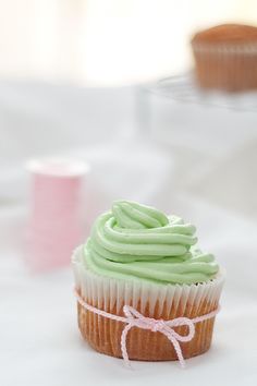 a cupcake with green frosting and pink sprinkles on the side