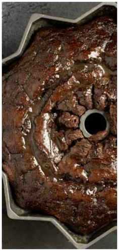 a chocolate cake in a metal pan with icing on top and some brownies around it