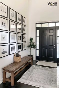 the entryway is decorated with black and white framed pictures, a bench, and a rug