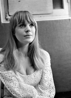 black and white photograph of a woman with long hair sitting on a couch looking at the camera