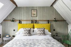 a bed with yellow pillows and white sheets in a room that has wood paneling on the walls