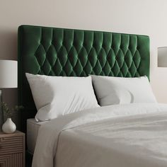 a green headboard with white sheets and pillows on a bed in front of a lamp