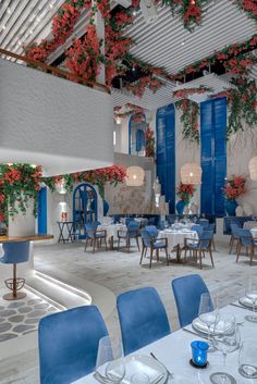 an indoor dining area with blue chairs and white tablecloths, flowers on the ceiling