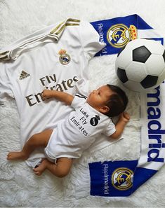 a baby is laying next to a soccer ball