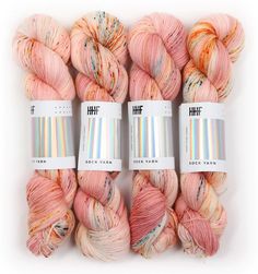 four skeins of yarn in different shades of pink, orange, and yellow