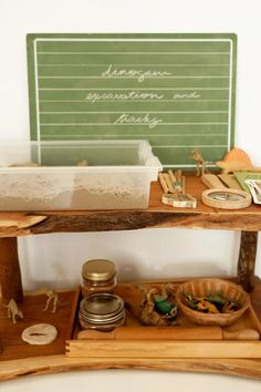 a wooden shelf with various items on it and a chalkboard in the back ground