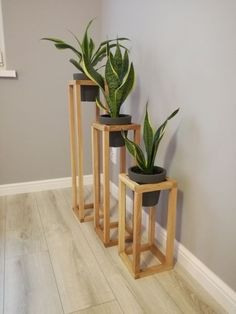 three wooden planters with plants in them sitting on the floor next to a wall