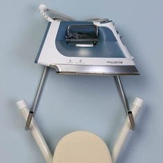 a white ironing board attached to a blue wall with an iron on it's side