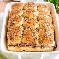 a white casserole dish filled with ham and cheese rolls