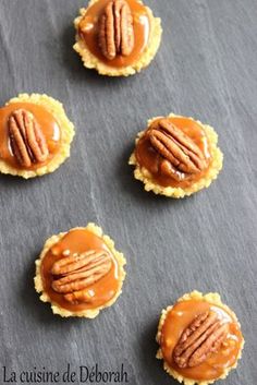 small desserts with caramel and pecans are arranged on a black tablecloth