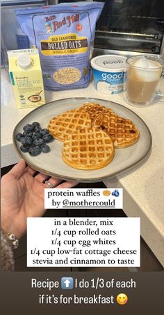 a person holding a plate with waffles and blueberries on it next to some milk