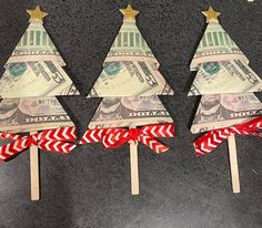 three christmas trees made out of money on top of toothpicks with red and white ribbons