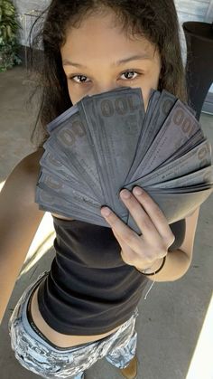 a woman holding up stacks of money in front of her face