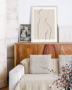 a living room filled with furniture and pictures on top of a wooden shelf next to a white couch