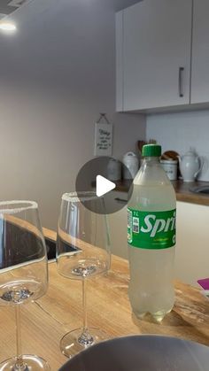 a bottle of spirt water sitting on top of a counter next to wine glasses