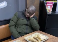 a man sitting at a table in front of a plate of food with the word donuts written on it