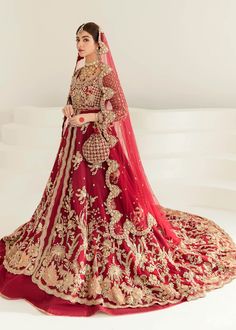 a woman in a red and gold bridal gown standing with her hands on her hips