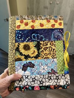 a person holding up a patchwork quilt with sunflowers and polka dots on it