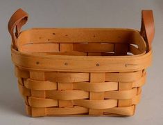 a wooden basket with leather handles on a table