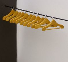 a row of yellow clothes hangers in front of a white wall