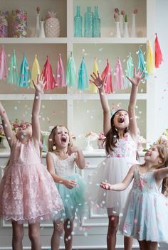 three girls in dresses are throwing confetti into the air with their hands and arms