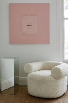 a white chair sitting in front of a pink painting