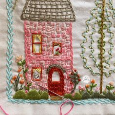 a pink house with trees and flowers in the background is embroidered on a white cloth