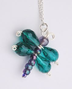 a green and purple dragonfly necklace on a silver plated chain with an amethorate bead