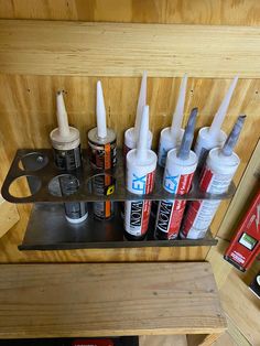 several different types of glues are on a metal shelf in a wood paneled room