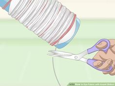 a person holding a pair of scissors and cutting strips of paper with the help of a plastic container