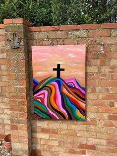 a brick wall with a painting on it and a cross hanging from the side of it