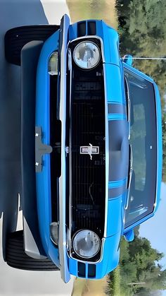 the front end of a blue car with its hood up and lights on is shown from above