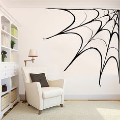 a living room with a chair and a spider web wall decal