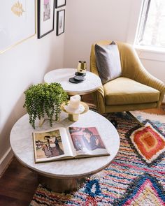 a living room with two chairs and a coffee table in the corner, along with pictures on the wall