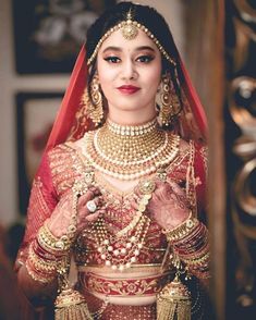 a woman in a red and gold bridal outfit