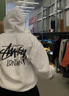 the back of a person's hoodie in a room with clothes on racks