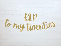 a white brick wall with gold foil lettering that says rip to my twenties