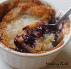 blueberry cobbler in a white bowl with a spoon resting on it's side