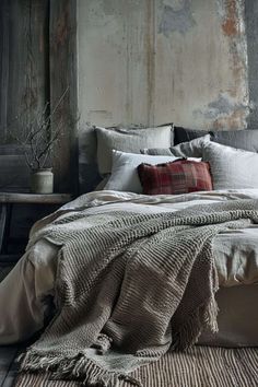 a bed with pillows and blankets on top of it in a room next to a wall