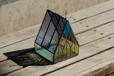 a stained glass house sitting on top of a wooden table