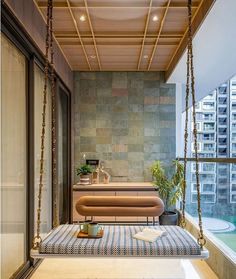 a living room filled with furniture next to a large glass window covered in plants and hanging from the ceiling