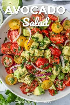 a white bowl filled with avocado salad on top of a table next to sliced tomatoes