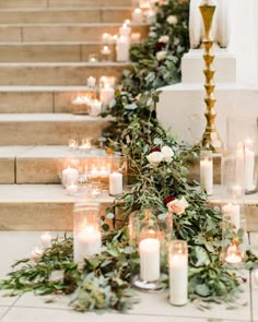 candles are lined up on the steps with greenery